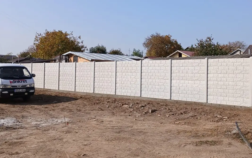 A Konkret Line autója egy rakott kő mintázatú fehér betonkerítés mellett