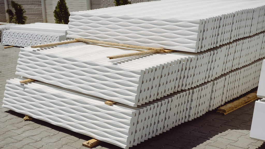 Fehér beton kerítéselemek egymásra rakva a gyár udvarán